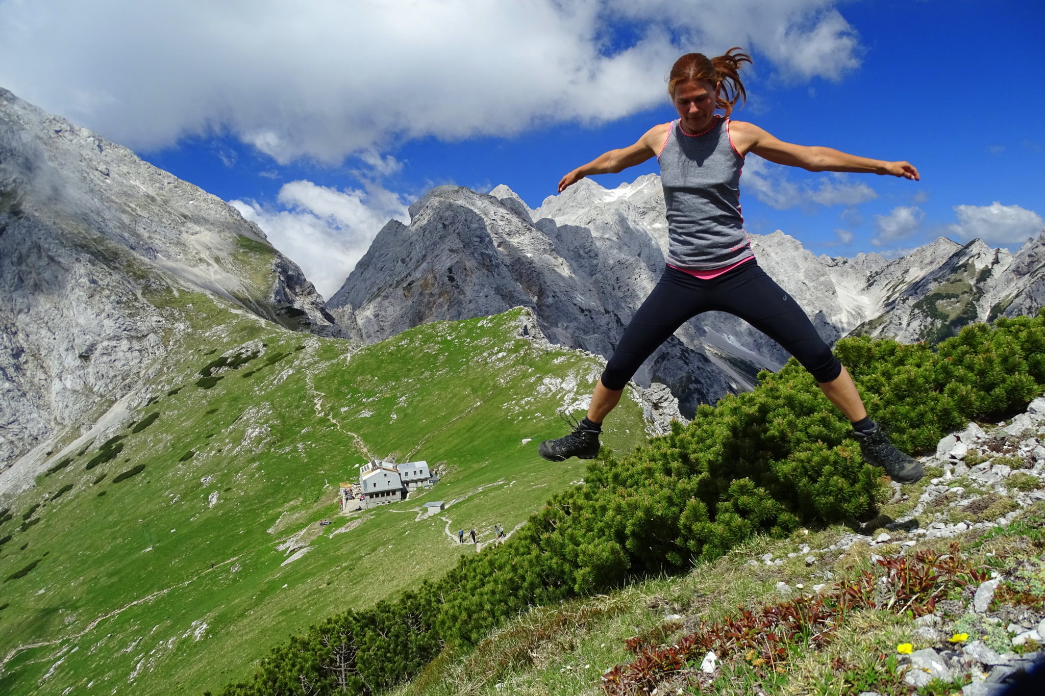 A woman hiker jumping with joy on an Alpine meadow