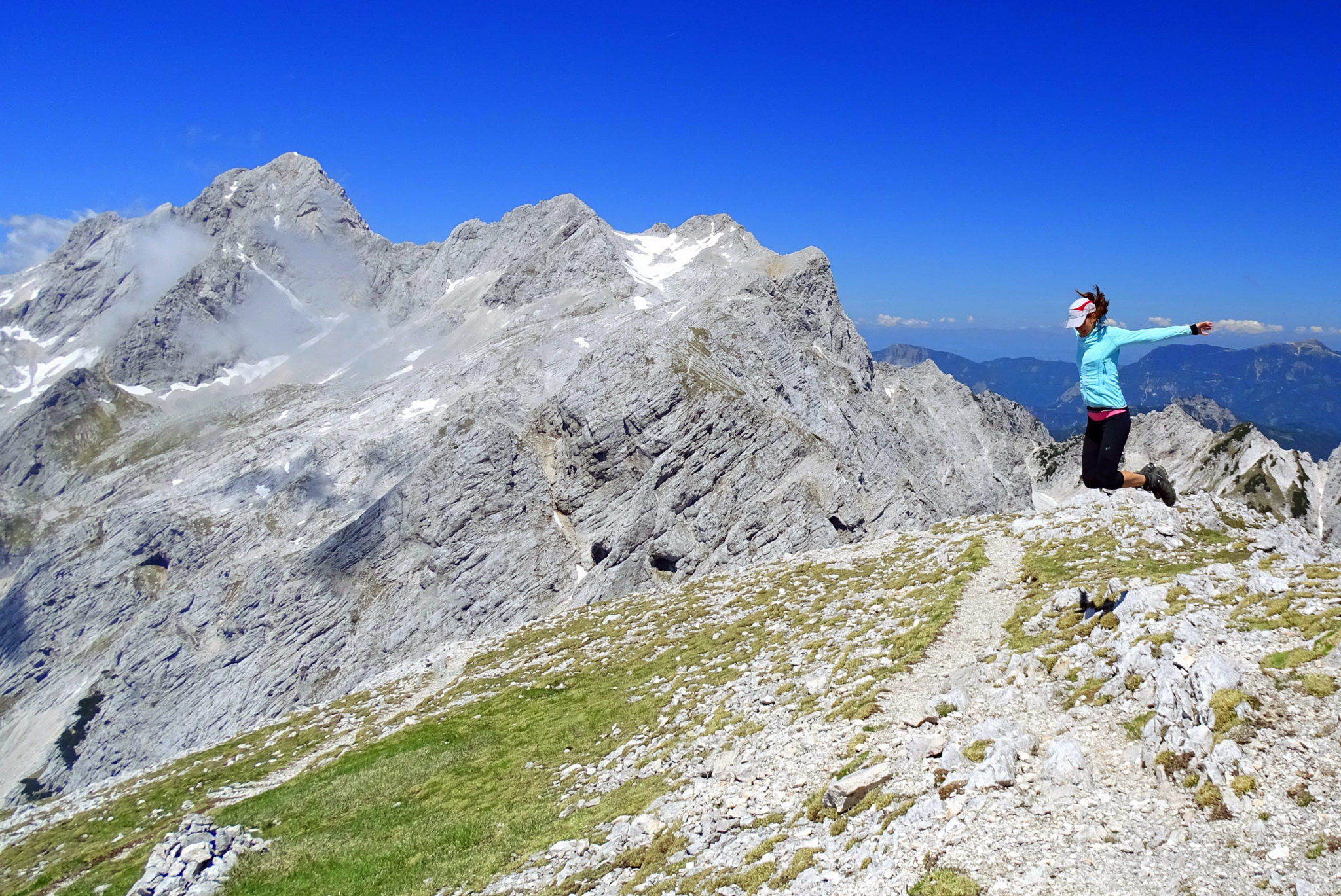 A woman hiker jumping with joy to have climbed a high mountain in Slovenia